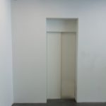 weiße Aufzugstür in weißer Wand
